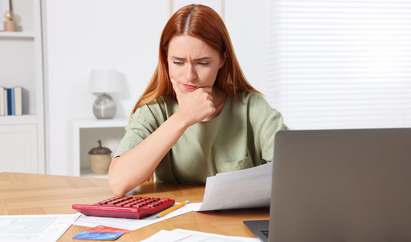 Woman thinking while looking at a letter and calculator