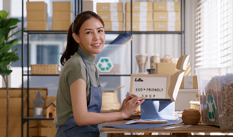 Woman surrounded by cardboard boxes and a recycling symbol