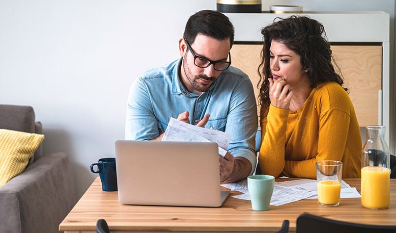 A couple sat at a kitchen table discussing a letter
