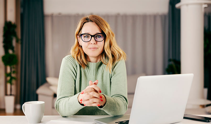 Self-employed woman sat at a table with her laptop.