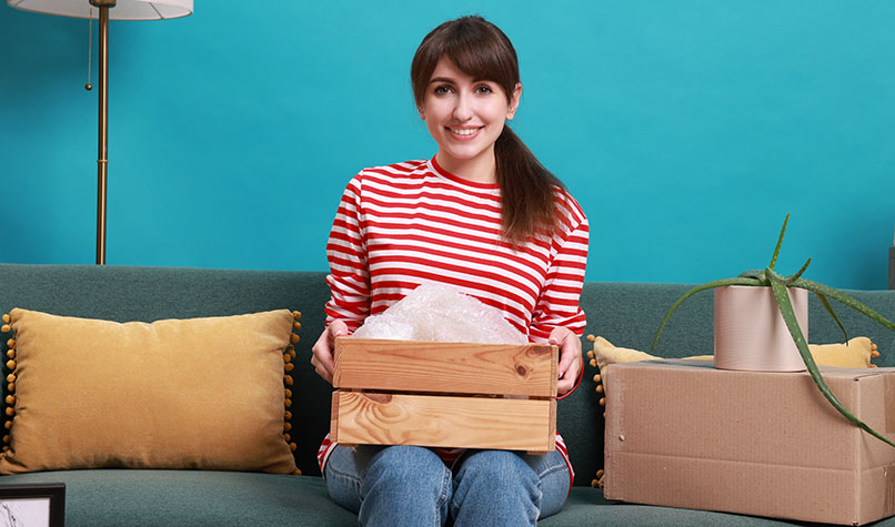 A woman sat on a sofa holding a box