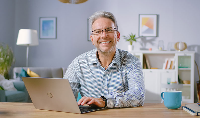 Man with grey hair working on his laptop on a desk