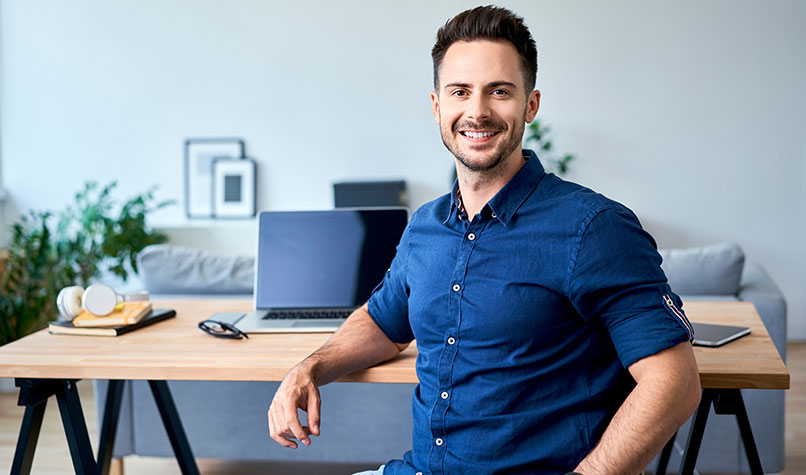 A man wearing a blue shirt sat down in front of his desk