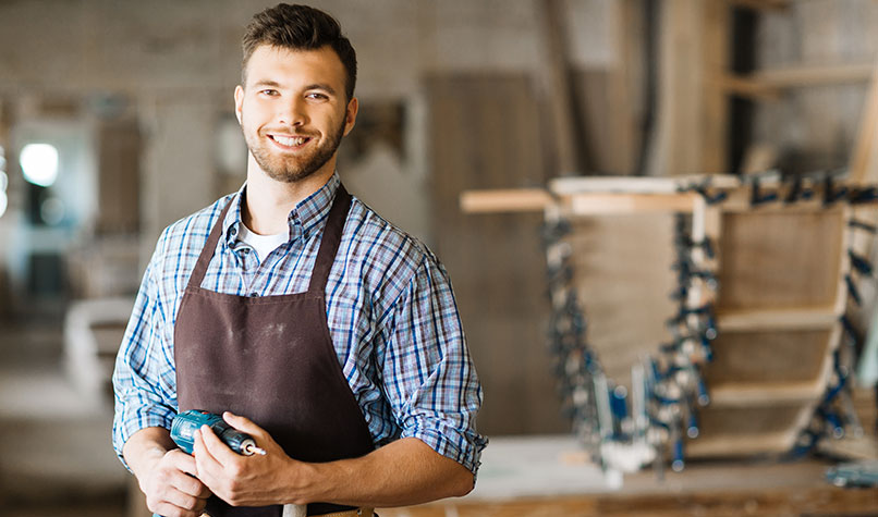A carpenter holding a power drill in his workshop
