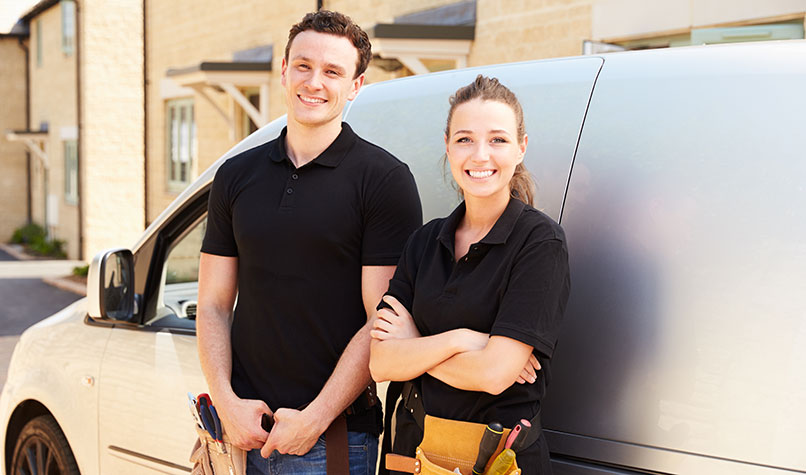 A man and a woman builder leaning against their white van