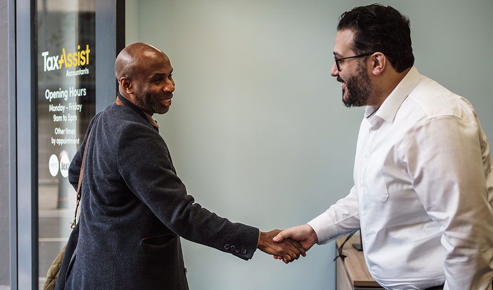 A client shaking hands with an accountant at a TaxAssist shop