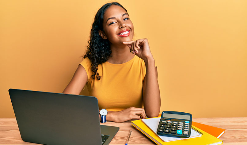 Woman sat a a desk thinking and smiling