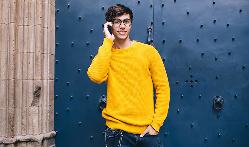 Man in a yellow jumper using a mobile phone