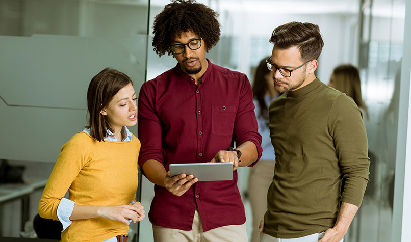 A woman and two men discussing what is on a tablet screen