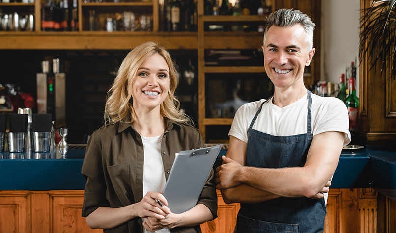 A man and woman standing in front of a pub bar