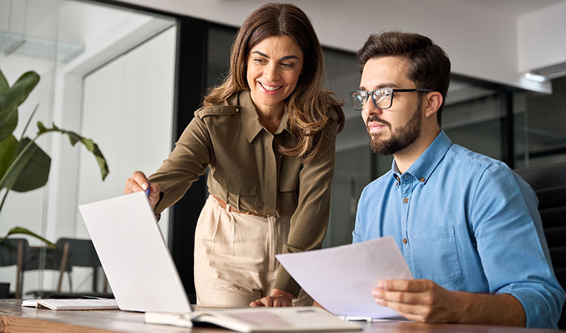 Woman showing male colleague laptop screen
