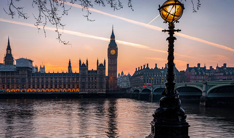 The UK Houses of Parliament at sunset pictured from across the Thames river.