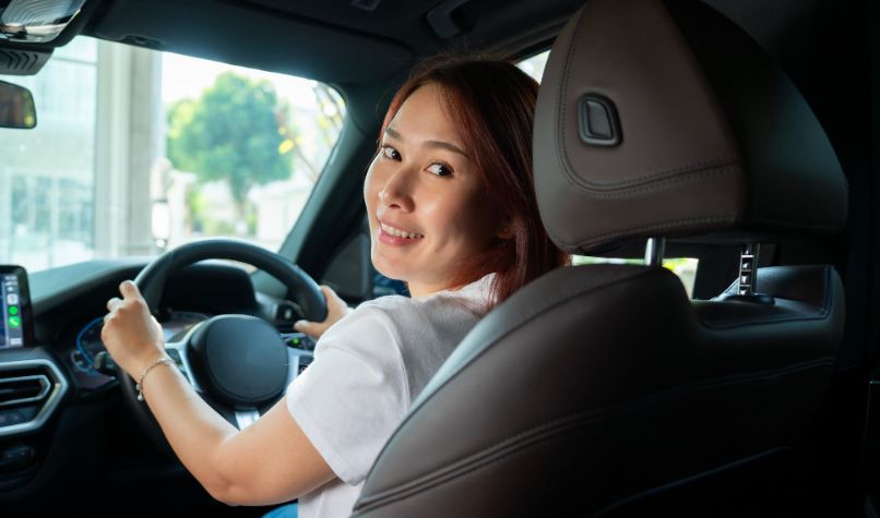 woman in car driving seat turning to look to the back seat