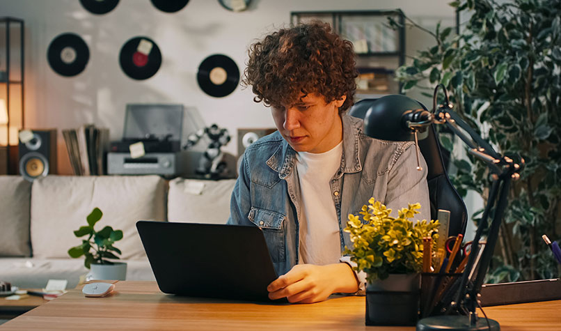 Man with curly hair looking at a laptop in a record store