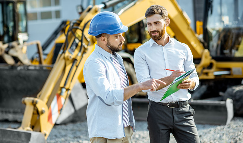 A builder buying a new piece of excavation machinery from a salesman.
