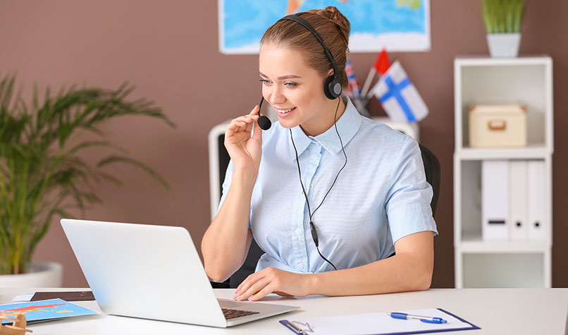 A woman wearing a headset while speaking to someone on a laptop.