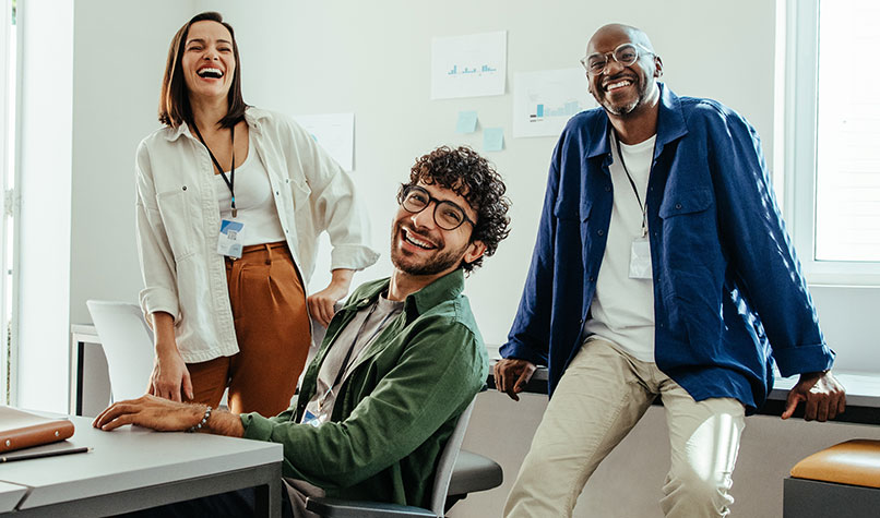 Three office employees in casual dress laughing