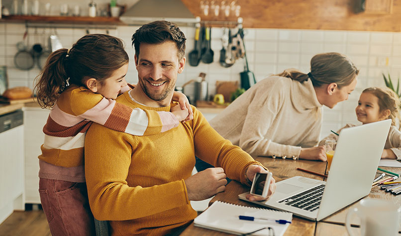 A father and mother with their two children sat at a kitchen table.