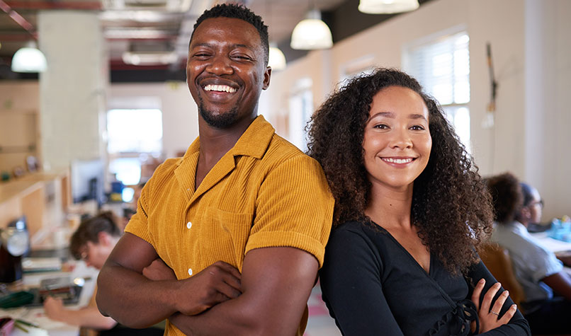 A man and woman standing together with their arms crossed in an office