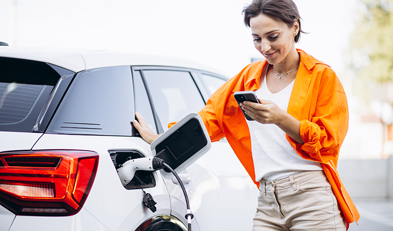 A woman in an orange shirt filling up her car