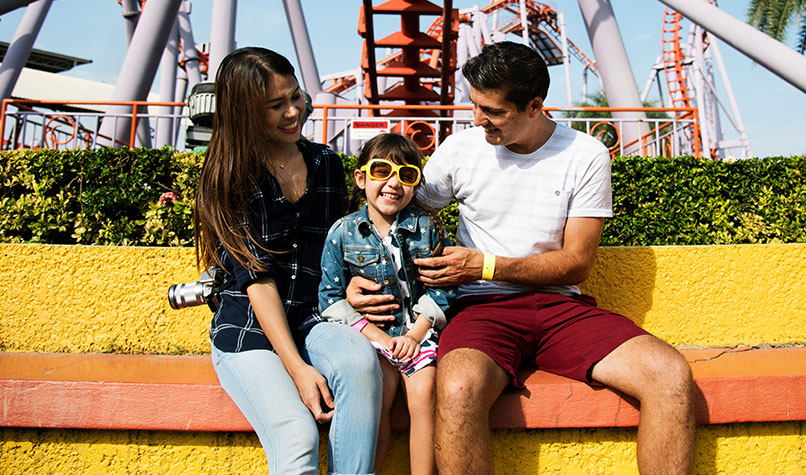 A man, woman and a child sat in a theme park