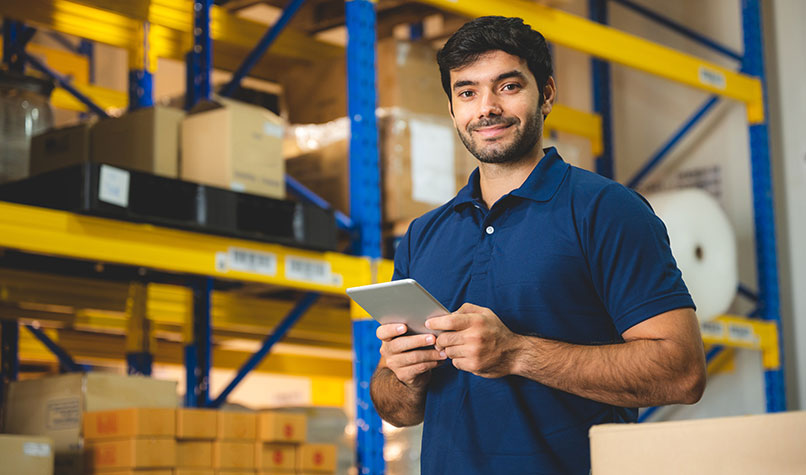 A male warehouse worker holding a tablet