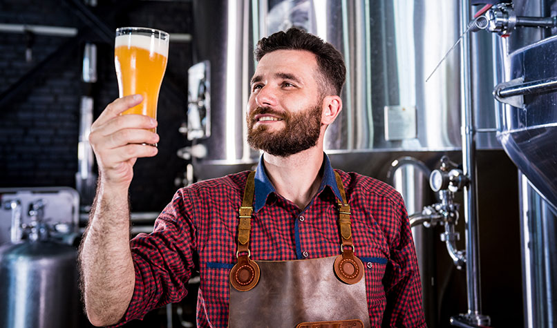 A craft brewer examining a pint of beer.