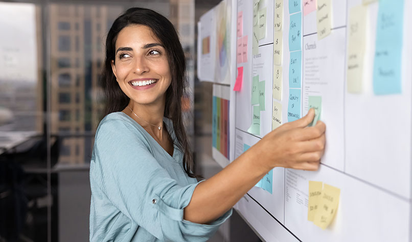 Woman sticking post-it notes onto a whiteboard.