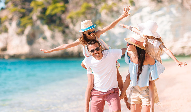 A father, a mother and their two children having fun on an exotic beach.