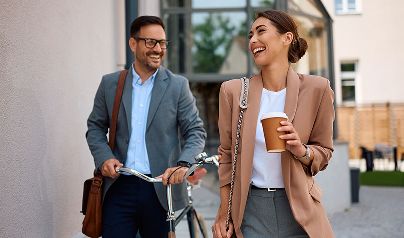 A man and woman laughing and walking away from an office building