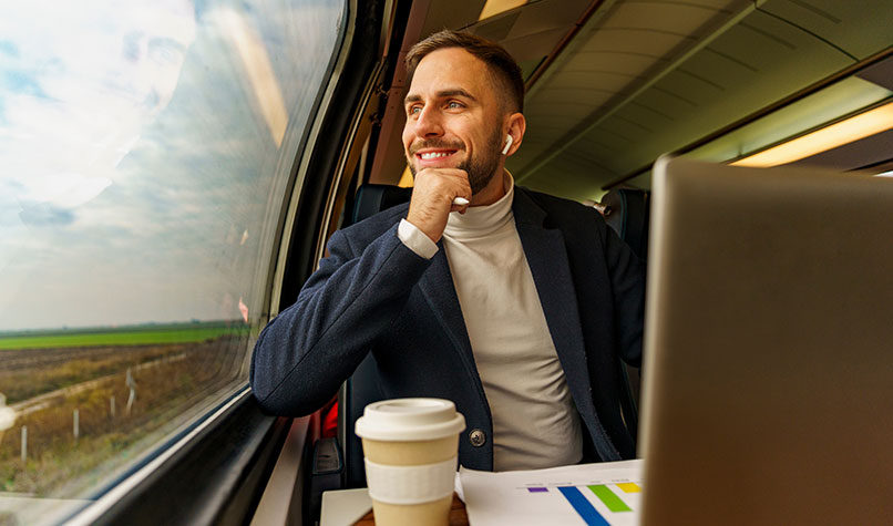 Man sat in a train looking out the window at the countryside.